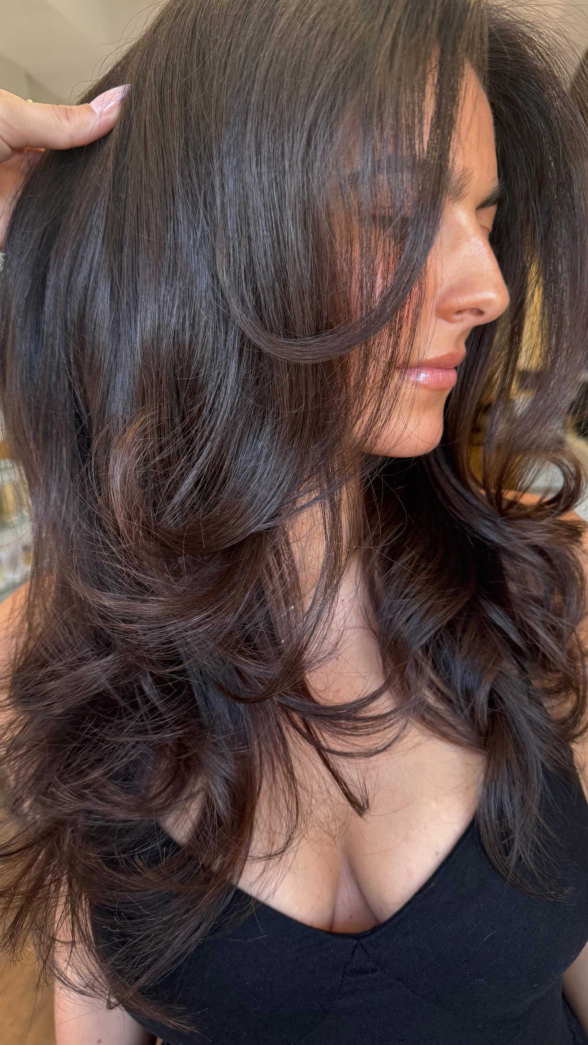 Sleek brunette hair with voluminous curls, styled for a polished look.