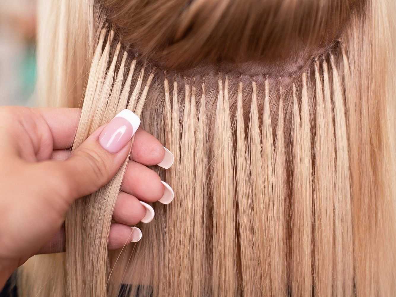Hair extensions being applied to blonde hair using a microbead technique.